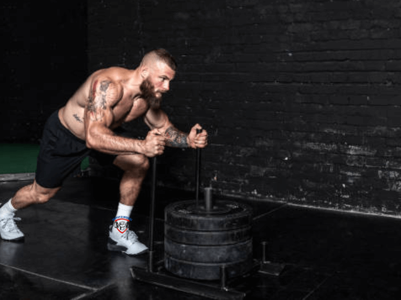 Athlete pushing a weighted sled, an advanced leg workout for strength and endurance